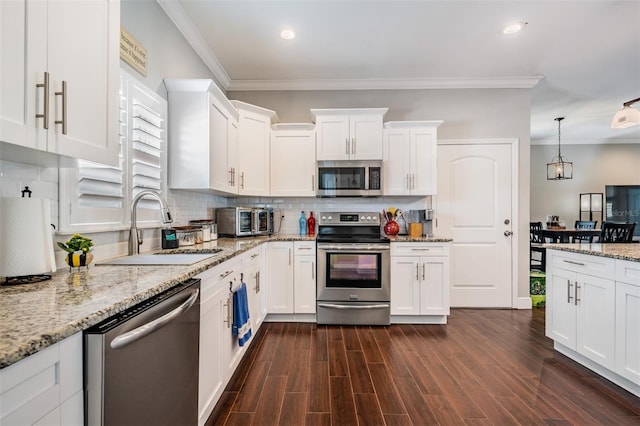 260 SW Lincoln Cir N, Saint Petersburg, FL 33703 - kitchen featuring appliances with stainless steel finishes, a sink, crown molding, white cabinetry, and backsplash