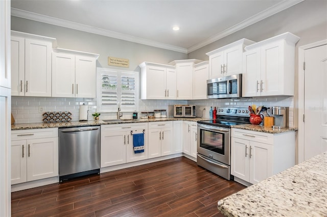 260 SW Lincoln Cir N, Saint Petersburg, FL 33703 - kitchen with appliances with stainless steel finishes, ornamental molding, white cabinetry, a sink, and dark wood-style floors