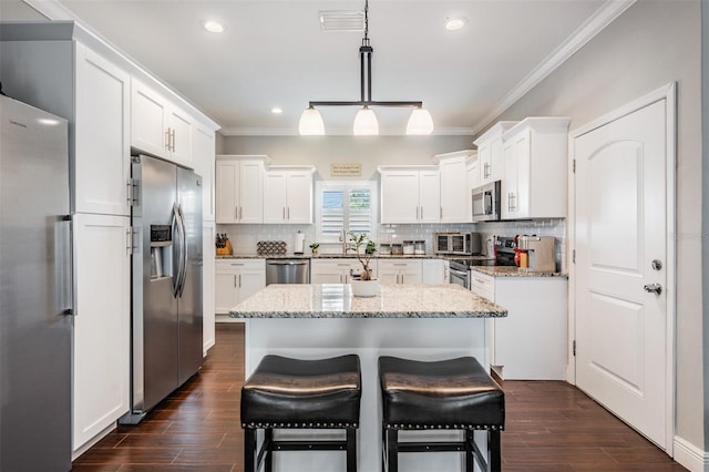 260 SW Lincoln Cir N, Saint Petersburg, FL 33703 - kitchen with stainless steel appliances, ornamental molding, a kitchen island, white cabinetry, and a sink