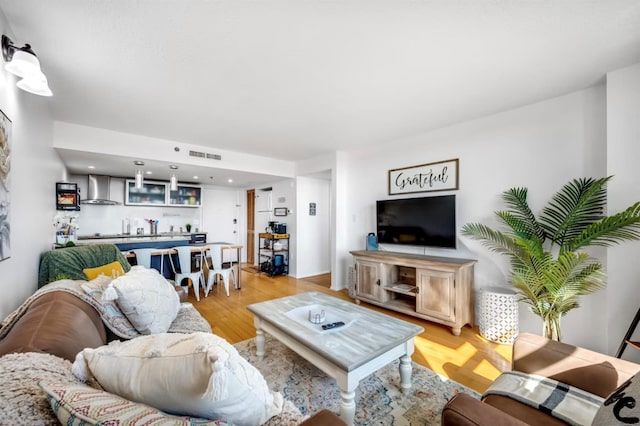 living area featuring wet bar, light wood finished floors, and visible vents