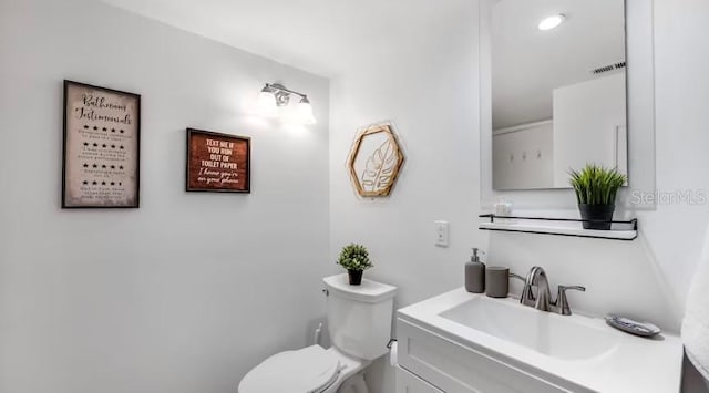 bathroom featuring toilet, vanity, and visible vents