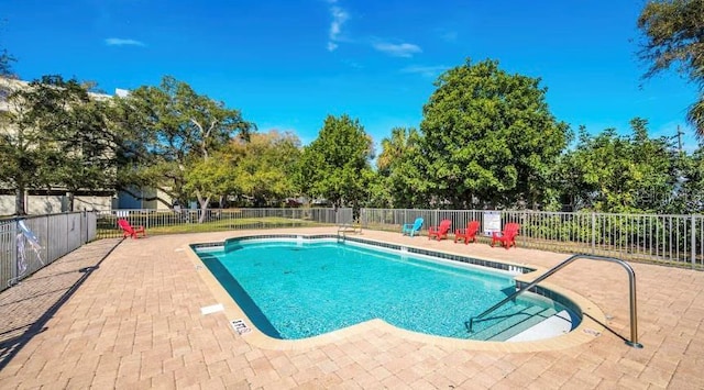 community pool with a patio area and fence