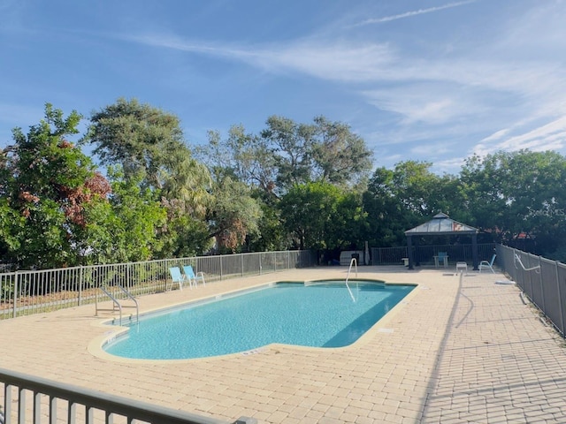 pool with a patio area, fence, and a gazebo