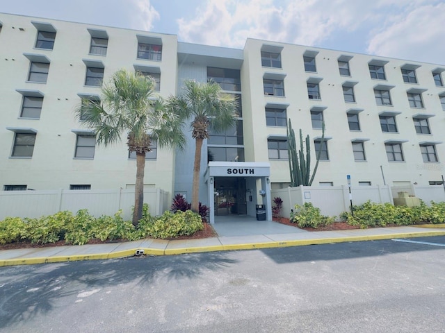 view of building exterior with fence and uncovered parking