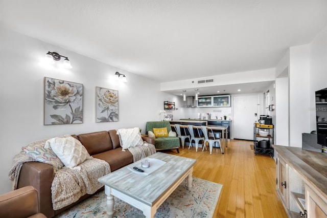 living room with light wood-style floors, visible vents, and indoor wet bar