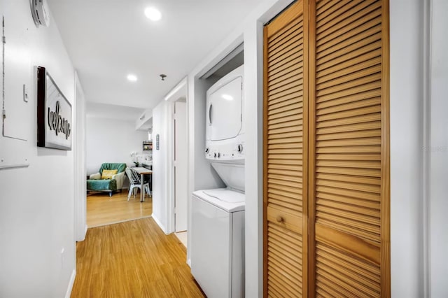 laundry area featuring laundry area, light wood-style flooring, stacked washer / drying machine, and recessed lighting