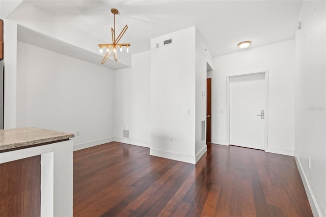 unfurnished dining area with a chandelier, dark wood finished floors, and baseboards