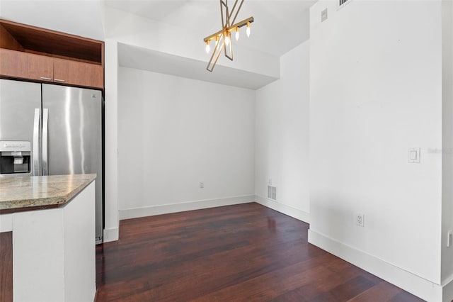 unfurnished dining area with a chandelier, dark wood-style flooring, and baseboards