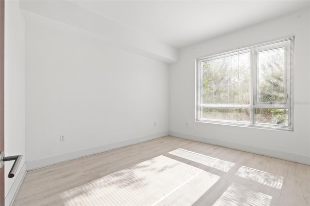 spare room featuring plenty of natural light, light wood-type flooring, and baseboards