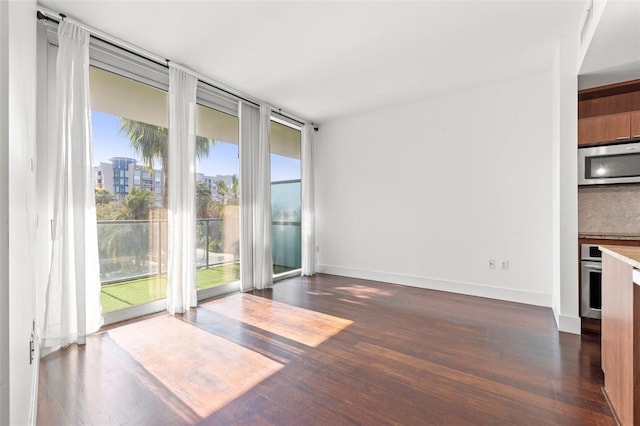 unfurnished room with dark wood-style floors and baseboards