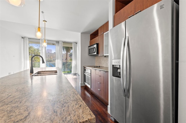 kitchen featuring appliances with stainless steel finishes, modern cabinets, a sink, brown cabinetry, and backsplash