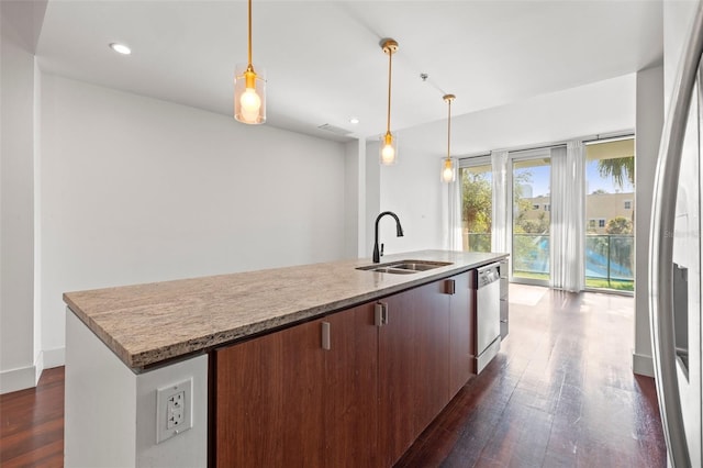 kitchen featuring dishwasher, a sink, dark wood-style flooring, a center island with sink, and light stone counters