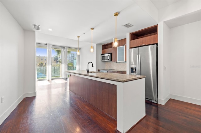 kitchen featuring stainless steel appliances, a sink, dark wood-style floors, baseboards, and a center island with sink