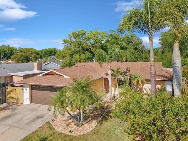 view of front of home featuring driveway, roof with shingles, a garage, and a gate