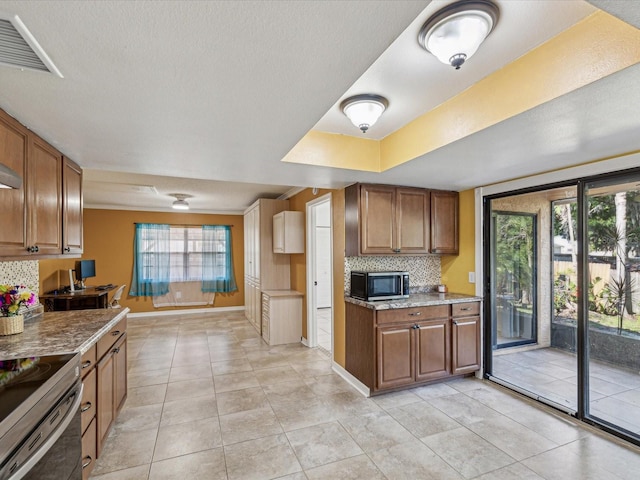 kitchen featuring baseboards, stainless steel range with electric stovetop, brown cabinets, and decorative backsplash