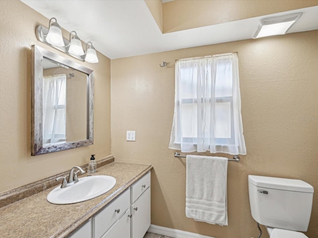 half bath with toilet, vanity, visible vents, and plenty of natural light
