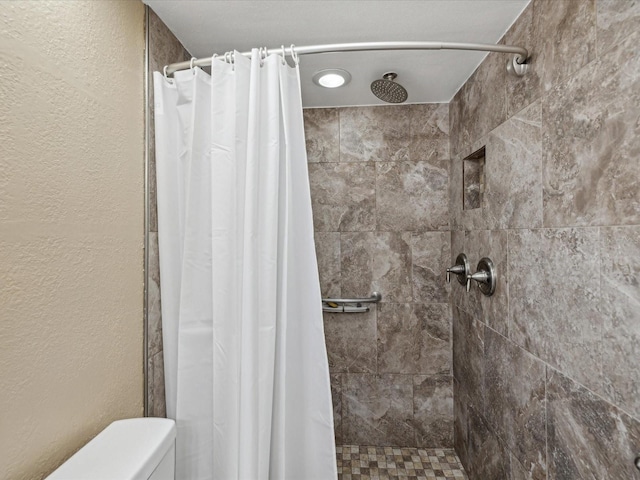 full bathroom featuring toilet and a stall shower