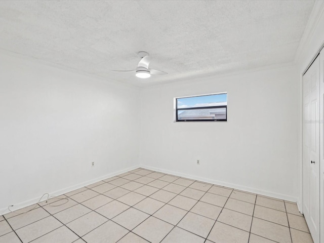 unfurnished room featuring a ceiling fan, baseboards, light tile patterned flooring, and a textured ceiling