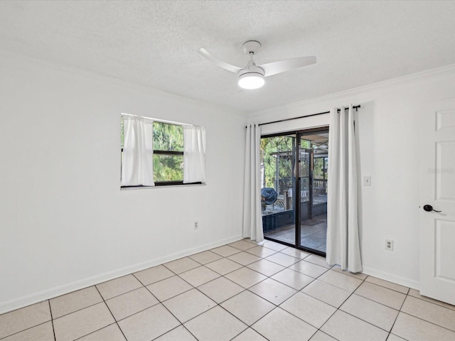 empty room featuring a ceiling fan, a textured ceiling, baseboards, light tile patterned floors, and crown molding