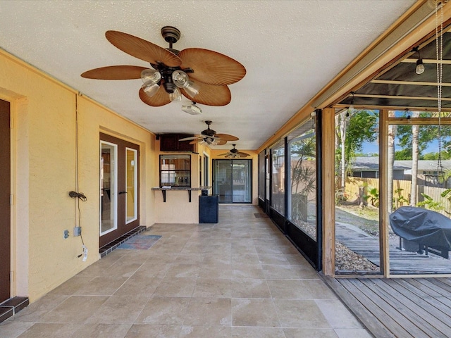 unfurnished sunroom featuring a ceiling fan and a textured ceiling