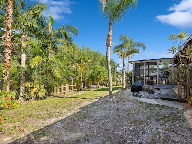 view of yard featuring a sunroom, fence, and a wooden deck