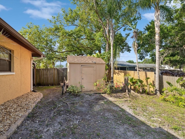 view of yard featuring a fenced backyard, an outdoor structure, and a storage shed