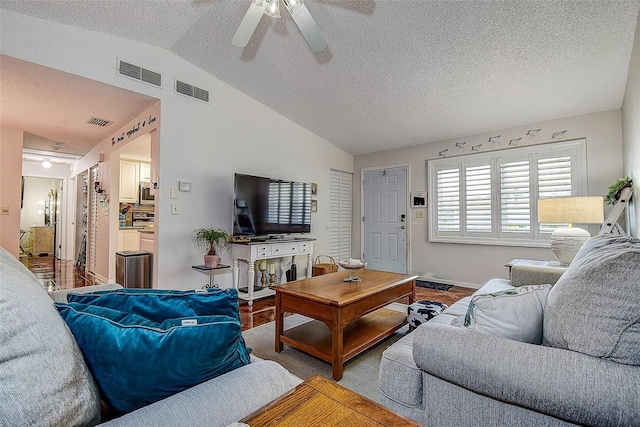 living room featuring lofted ceiling, ceiling fan, a textured ceiling, and baseboards