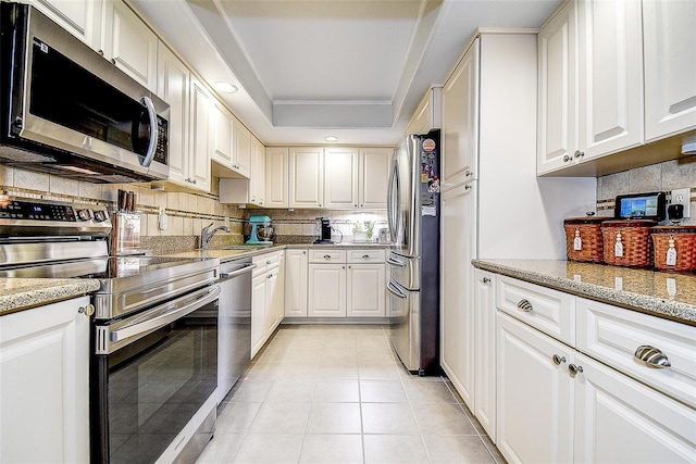 kitchen featuring appliances with stainless steel finishes, backsplash, a sink, and white cabinetry