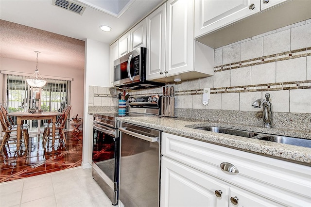 kitchen featuring stainless steel appliances, backsplash, a sink, light tile patterned floors, and light stone countertops