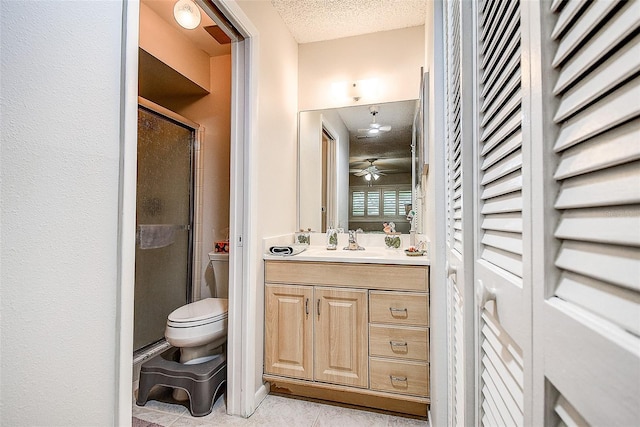 full bathroom featuring a textured ceiling, a stall shower, toilet, vanity, and tile patterned flooring