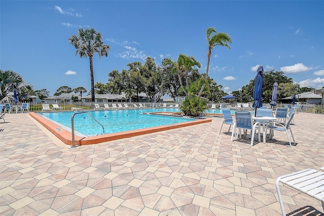 community pool with fence and a patio area