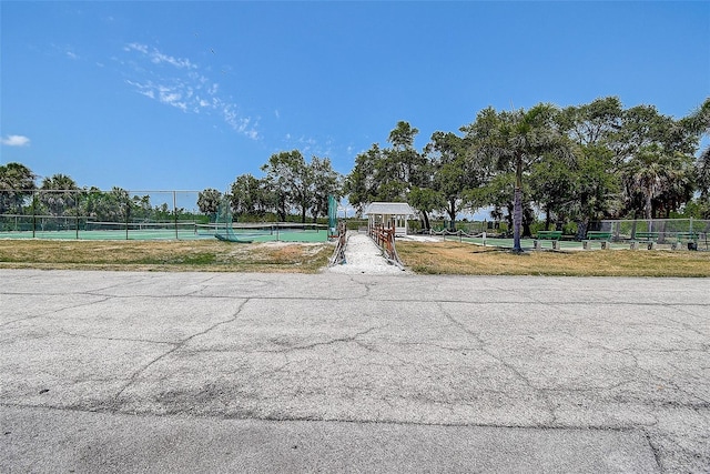view of community with a tennis court and fence