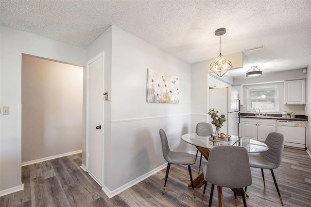 dining room featuring a textured ceiling, dark wood-type flooring, and baseboards
