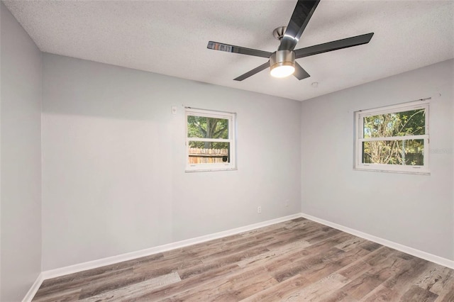 unfurnished room with a wealth of natural light, a textured ceiling, and wood finished floors