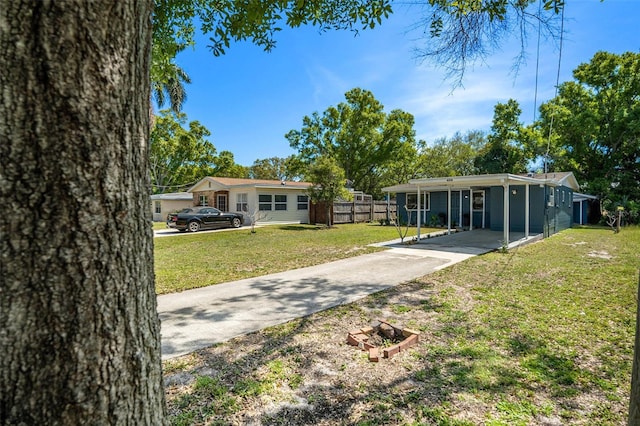 view of front of house featuring concrete driveway, a front yard, an attached carport, and fence