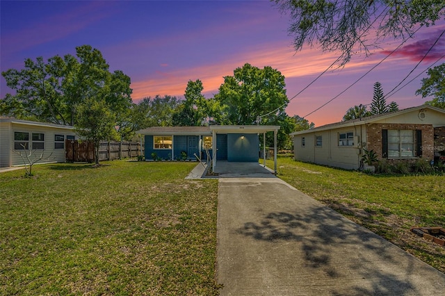 view of front of home featuring an attached carport, fence, a front yard, brick siding, and driveway
