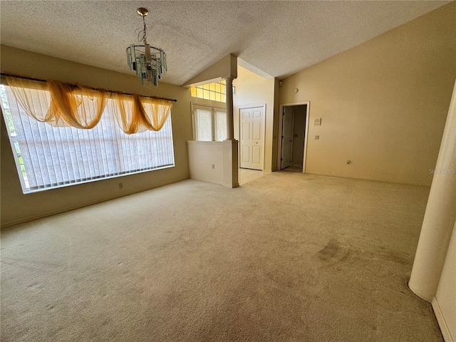 spare room with vaulted ceiling, an inviting chandelier, a textured ceiling, and carpet