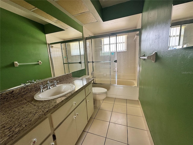 full bath with toilet, tile patterned flooring, vanity, and shower / bath combination with glass door