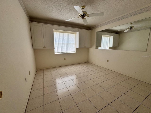 empty room with ceiling fan, a textured ceiling, and light tile patterned flooring