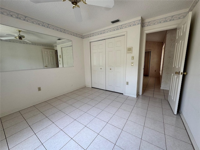 unfurnished bedroom with a closet, a textured ceiling, visible vents, ceiling fan, and light tile patterned flooring