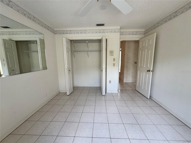 unfurnished bedroom featuring light tile patterned floors, a closet, a textured ceiling, visible vents, and ceiling fan