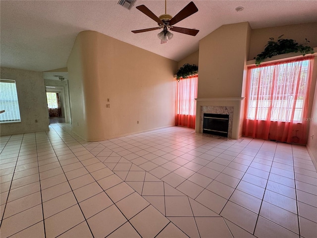 unfurnished living room featuring a high end fireplace, a textured ceiling, vaulted ceiling, a ceiling fan, and light tile patterned floors