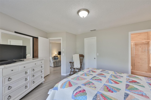 2115 N Halcyon Dr Unit 510, Sun City Center, FL 33573 - bedroom featuring light wood-type flooring, a textured ceiling, connected bathroom, and baseboards