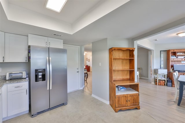 2115 N Halcyon Dr Unit 510, Sun City Center, FL 33573 - kitchen featuring stainless steel refrigerator with ice dispenser, white cabinetry, baseboards, and light stone counters