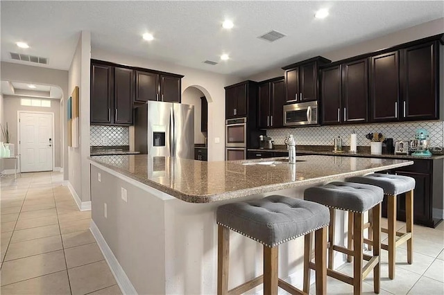 4407 Scarlet Loop, Wesley Chapel, FL 33544 - kitchen featuring stainless steel appliances, arched walkways, a sink, light tile patterned floors, and recessed lighting