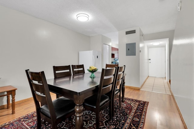 7505 Pitch Pine Cir Unit 122, Tampa, FL 33617 - dining room featuring a textured ceiling, baseboards, visible vents, electric panel, and light wood-type flooring
