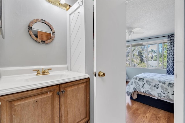 7505 Pitch Pine Cir Unit 122, Tampa, FL 33617 - ensuite bathroom featuring a textured ceiling, ceiling fan, connected bathroom, vanity, and wood finished floors