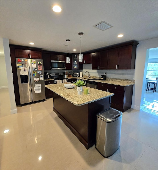 kitchen with appliances with stainless steel finishes, recessed lighting, light stone counters, hanging light fixtures, and a kitchen island