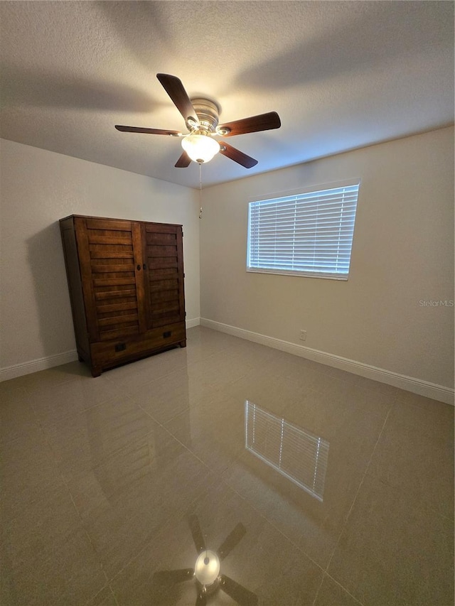 unfurnished bedroom with a ceiling fan, baseboards, and a textured ceiling