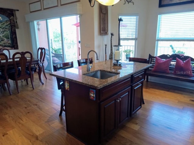 6926 Mccray Dr, Hudson, FL 34667 - kitchen with a sink, wood finished floors, a breakfast bar area, light stone countertops, and an island with sink